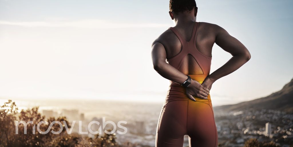 Lower Back Pain Orlando - Psoas Release at Moov Labs in Orlando, Florida Black woman holding lower back in pain on mountain top — promoting psoas release and lower back relief services at Moov Labs Orlando.