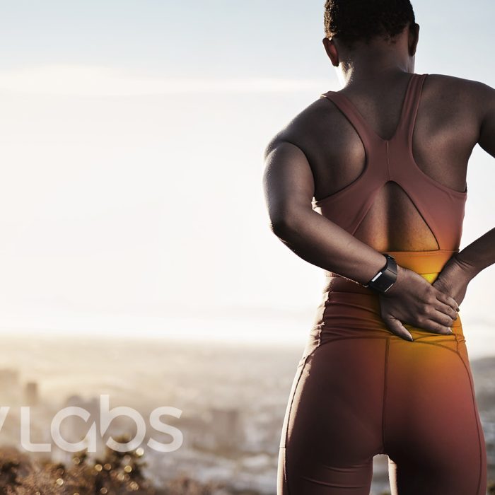 Lower Back Pain Orlando - Psoas Release at Moov Labs in Orlando, Florida Black woman holding lower back in pain on mountain top — promoting psoas release and lower back relief services at Moov Labs Orlando.