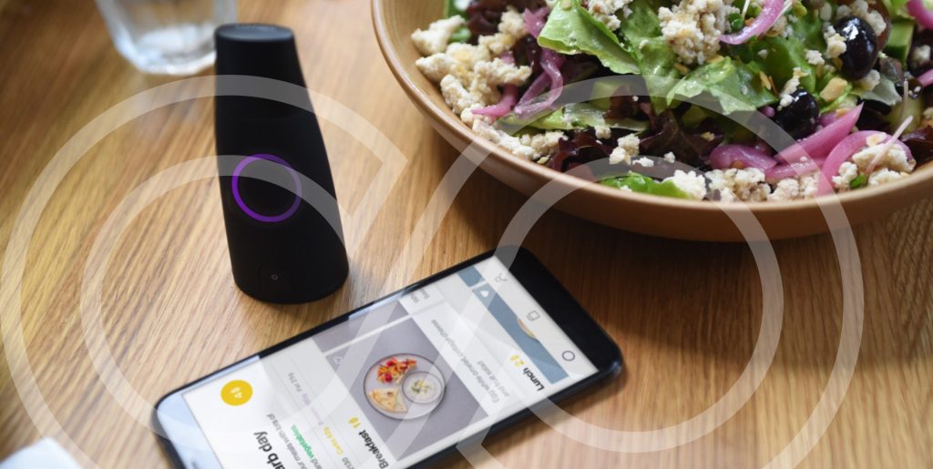 Lumen metabolic tracking device next to a smartphone and a healthy salad, illustrating metabolic testing and nutrition insights at Moov Labs in Orlando.