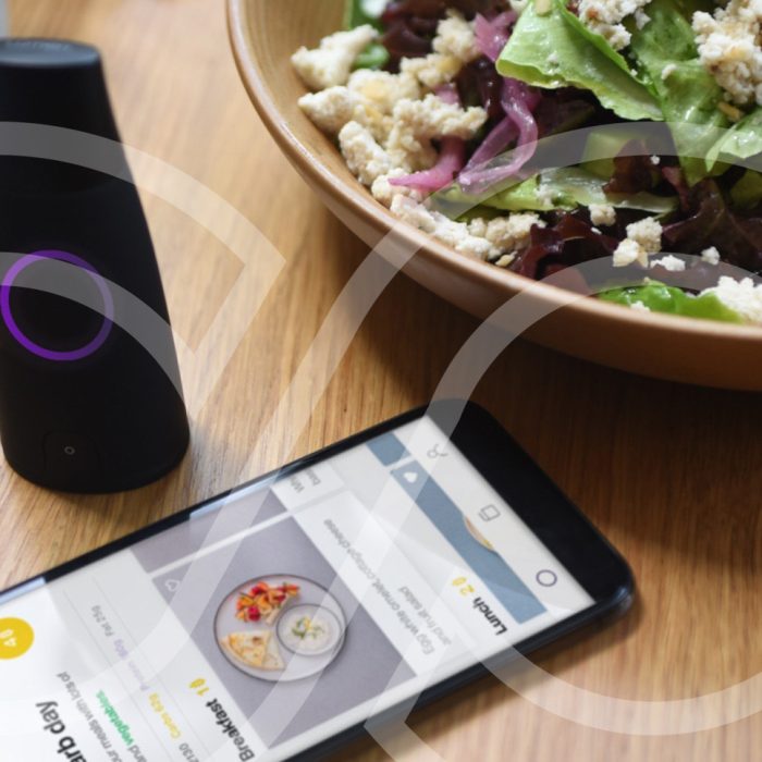 Lumen metabolic tracking device next to a smartphone and a healthy salad, illustrating metabolic testing and nutrition insights at Moov Labs in Orlando.